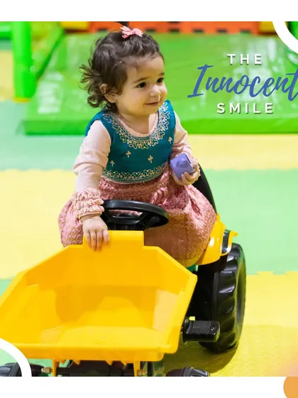 The innocent smile. This little one is enjoying a ride on the mini-tractor, completely lost in her own world of play.