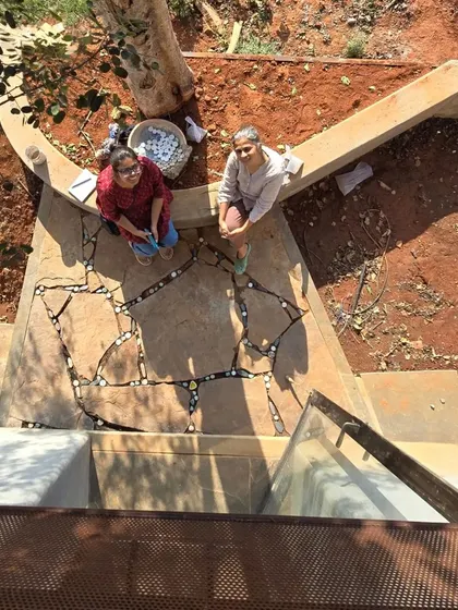 A moment of quiet collaboration, laying tile inserts into the stone flooring by the tree. These small, handmade details are what give a space its unique character and warmth.