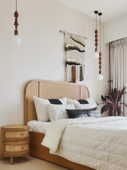 We designed this room for the grandmother of the family, using natural rattan furniture and a woven wall hanging to create a warm, earthy, and personal space. The pendant lights add a touch of modern craftsmanship.
