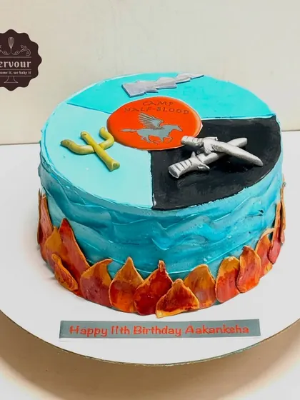 A Percy Jackson-themed cake for an 11th birthday. The design is divided into sections representing different elements from the book series, including the Camp Half-Blood logo and Poseidon's trident.