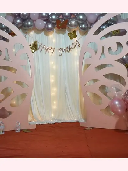 The centerpiece of our butterfly theme is this beautiful photo backdrop. The giant pink butterfly wings, shimmering curtain, and metallic balloon arch create a whimsical setting for the birthday girl.