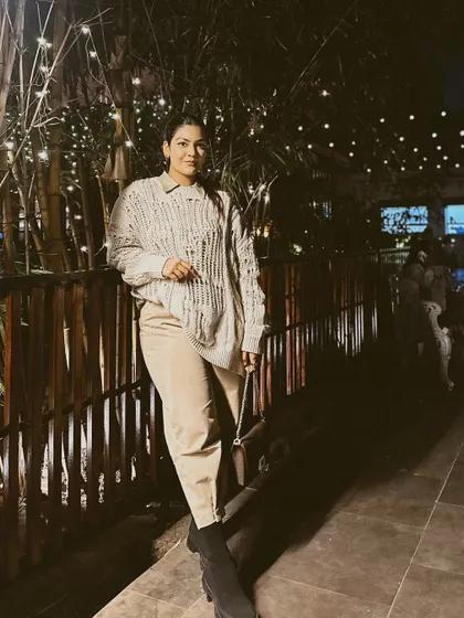 A cozy and chic look for a night out. A distressed knit sweater paired with beige trousers and chunky black boots.