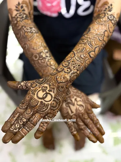This engagement design features interlocking rings on one palm and the couple's initials 'MS' on the other, surrounded by detailed floral and geometric patterns.