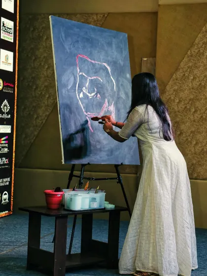 The process begins. Here I am on stage, laying down the initial outlines for a portrait of Puneeth Rajkumar. This is the quietest moment before the energy builds.