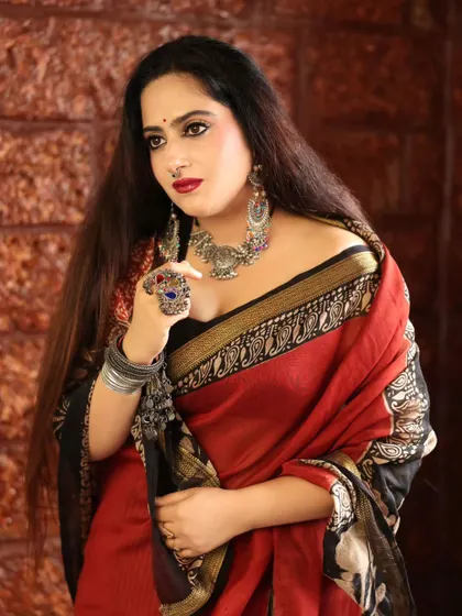 An elegant portrait of a model in a red and black saree. The oxidized silver jewelry and her poised expression create a look of timeless grace and sophistication.