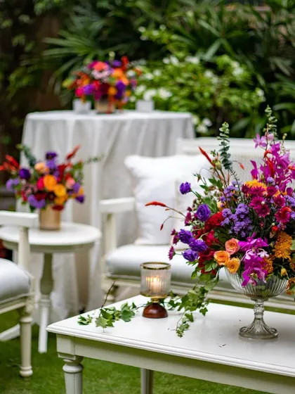 Another view of the garden party seating, with multiple arrangements of vibrant flowers adding pops of color throughout the space. The design feels lush, cheerful, and sophisticated.