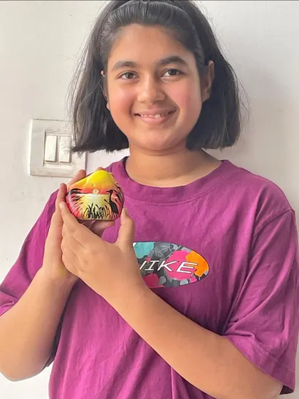A student proudly holding her sunset-themed painted rock. It's amazing how a simple stone can be turned into a tiny piece of art.