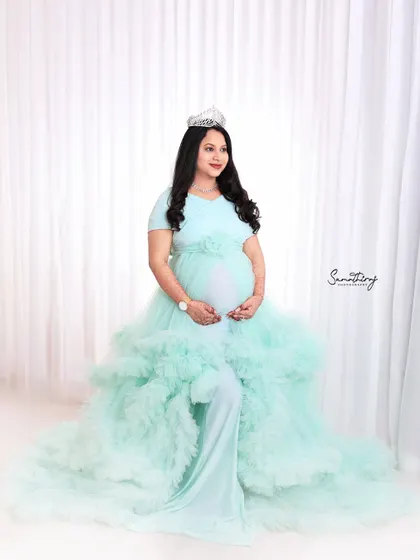 A regal portrait of a mother-to-be in a mint green gown, complete with a tiara. The high-key lighting and her poised expression create a look of pure elegance and grace.