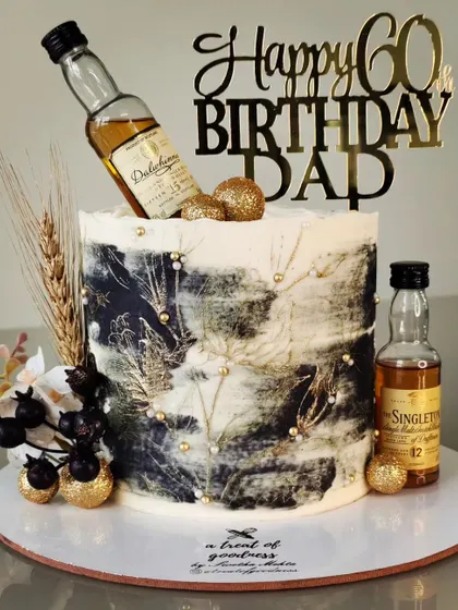 This cake was designed for a 60th birthday, featuring a masculine, abstract black and gold texture. I incorporated the celebrant's favorite whiskey miniatures and wheat accents for a personal touch.