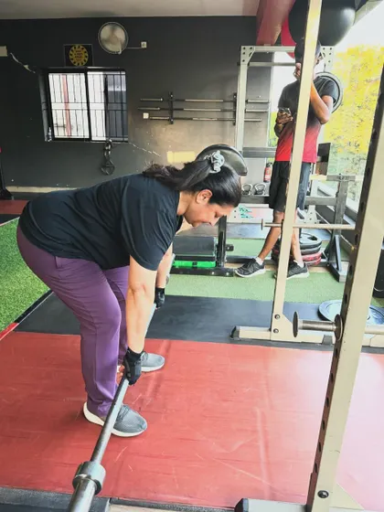 A client performs a deadlift, focusing on maintaining a flat back and proper form throughout the movement.