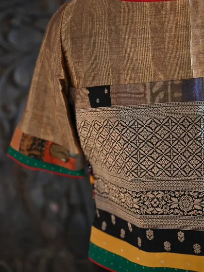 A detailed close-up of the blouse's back, where you can appreciate the intricate weave of the Banarsi silk and the colorful patchwork trim on the sleeves.