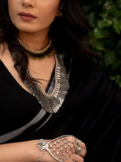 A close-up on the stunning, layered necklace and hand jewelry. This type of shot is perfect for showcasing artisan craftsmanship in a jewelry lookbook.