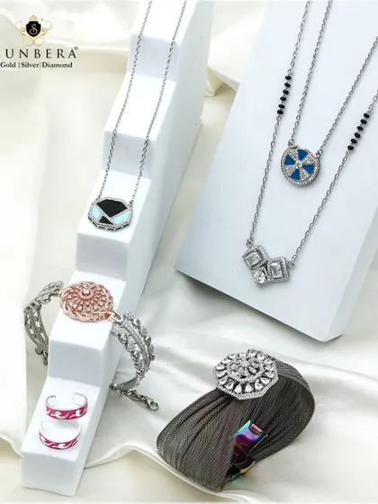 Shimmer with sophistication. This professionally styled shot displays a variety of our silver jewellery pieces on modern white stands. It includes necklaces, bracelets, rings, and a brooch, highlighting the breadth of our design capabilities for everyday fashion.