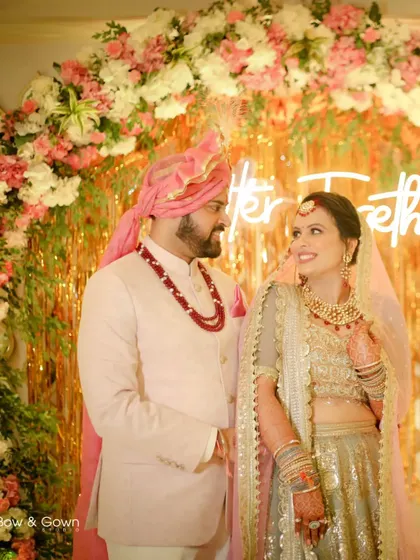 A beautiful wedding portrait of the couple in front of a floral arch with a neon sign. Their loving gaze and the modern decor create a stylish and romantic photo.