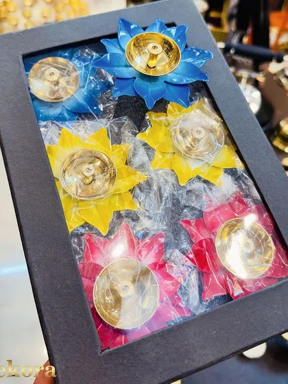 A gift box containing six brass diyas in bright, assorted colors. As manufacturers, we can package our products in various configurations to meet your specific bulk gifting needs.