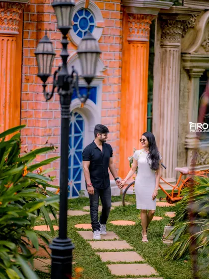 A romantic walk through a garden path. The couple's coordinated black and white outfits look chic and timeless in this classic pre-wedding photo.