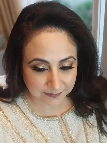 Here, the client looks down, showing the delicate shimmer on the eyelids and the precision of the eyeliner, adding a touch of glamour to the look.