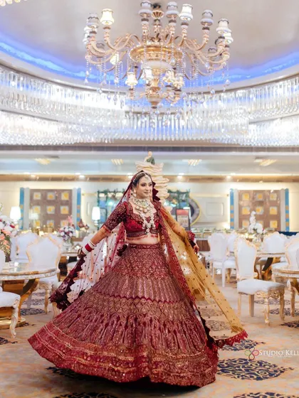 A full-length shot of the bride twirling in her magnificent red lehenga, under a grand chandelier.