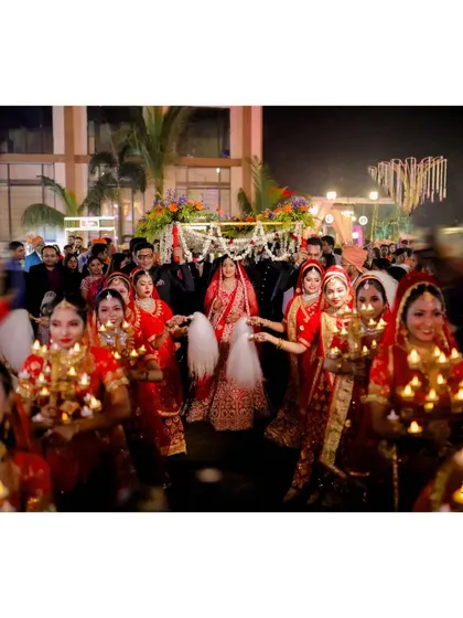 The bride's grand entrance under a phoolon ki chadar, surrounded by women holding candles.