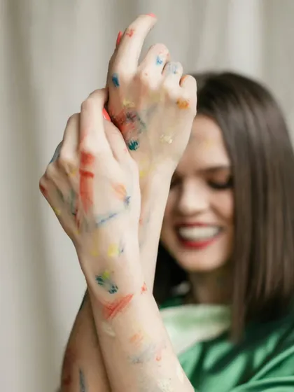 A joyful, out-of-focus shot capturing a genuine smile, with the focus on the color-stained hands, representing the playful nature of Holi.