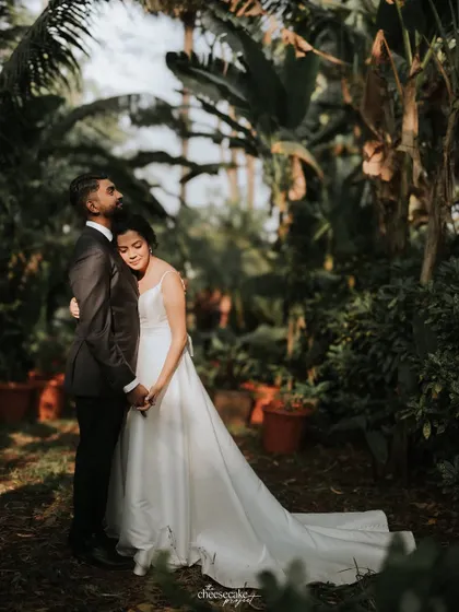 A tender moment between the couple, surrounded by the deep greens of a botanical garden.