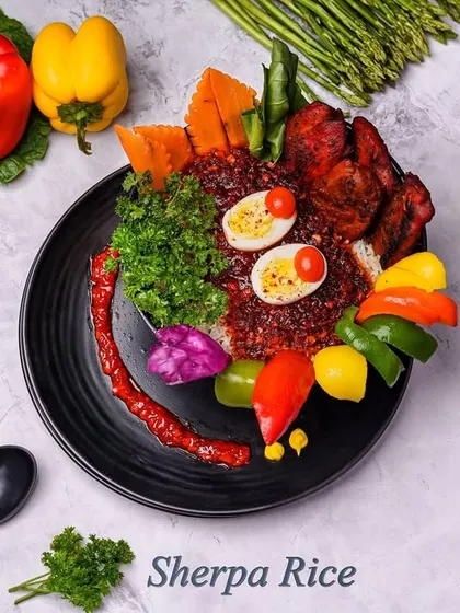 Sherpa Rice is a visually stunning and hearty meal. A bed of rice is topped with a spicy red gravy, grilled chicken, boiled eggs, and a colorful assortment of fresh and pickled vegetables.