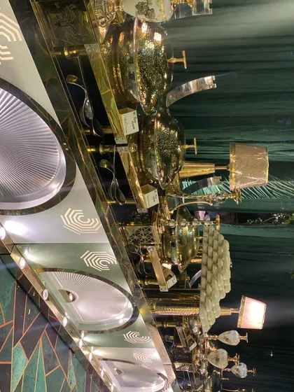 An angled shot of our buffet counter at a Dhol night event. The focus is on the gleaming gold chafing dishes and decorative table lamps that add warmth and elegance to the food display.