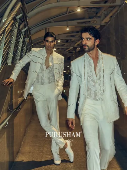 An all-white look from the 'Late Check Out' collection, proving that after-hours elegance isn't limited to dark colors. The focus here is on the sharp, power-shoulder silhouette and subtle linear embroidery, paired with a sheer, patterned shirt.