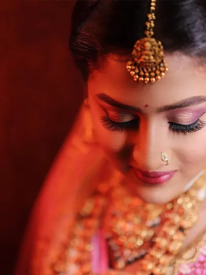 A dramatic close-up portrait of a bride, using warm, focused light to highlight her features and traditional gold jewellery. This technique creates a rich, painterly effect perfect for bridal photography.