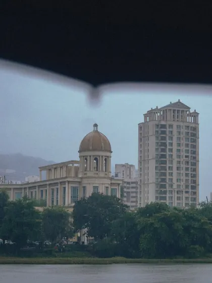 A view of Hiranandani, Powai, framed by an umbrella. The architecture looks almost like a painting through the soft, grey light of the monsoon.