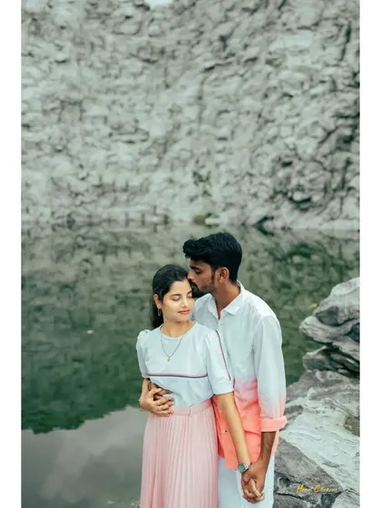A tender moment with the groom kissing the bride's forehead, set against the dramatic landscape of a rock quarry and a still lake.