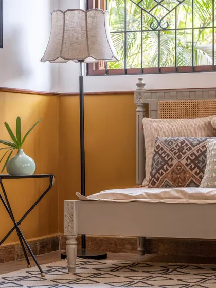 A bedroom in the Goan villa, featuring a half-painted mustard wall and a classic daybed. The design is simple, relaxed, and perfect for a holiday home.