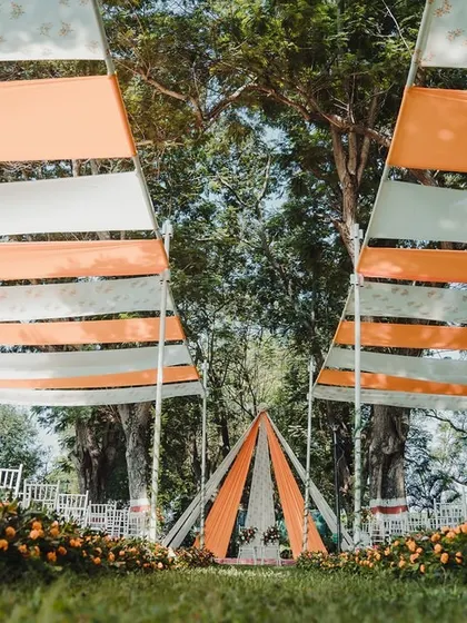 We used flowing drapes in orange and white to create a beautiful overhead canopy, leading the eye towards a simple and elegant teepee-style mandap for this outdoor wedding.