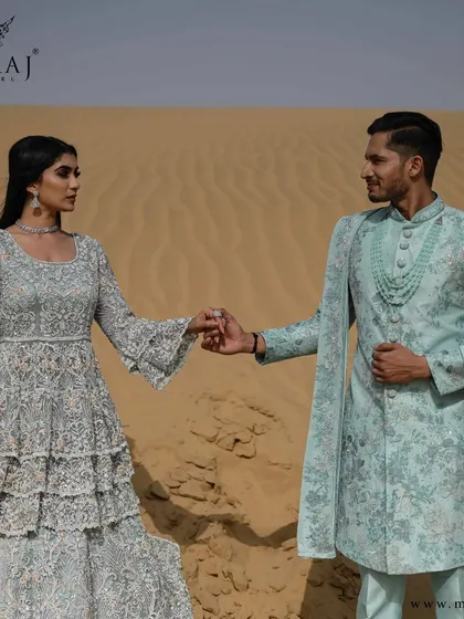 A glamorous sea-green Indo-Western gown with silver zardozi work is perfectly paired with a matching sherwani, creating a realm of elegance for the modern couple.