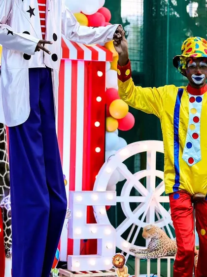 A clown and a stilt walker posing in front of the main stage, showcasing the professional entertainers I work with to elevate the party experience.