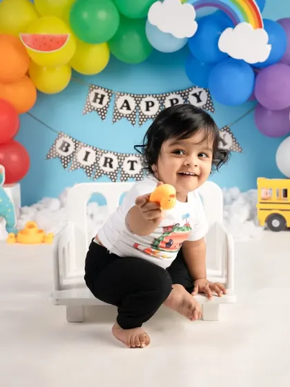 A big, happy smile from the birthday boy during his Cocomelon-themed shoot. The colorful balloons and props make the scene so vibrant.