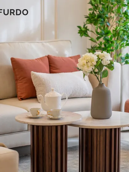 A close-up of our attention to detail in this living room. The fluted wood base of the coffee tables adds texture, while the soft furnishings in terracotta and white create a warm and inviting color scheme.