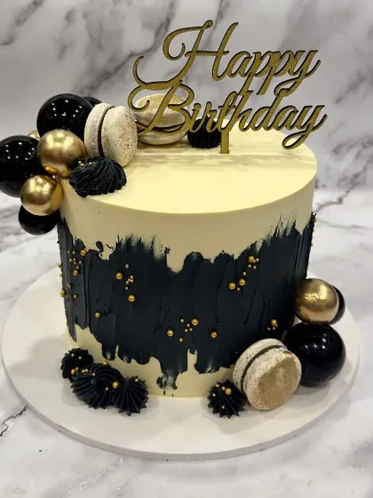 Another take on the black and gold theme, this time with the addition of elegant macarons. The abstract black buttercream and gold accents create a chic and modern birthday cake.