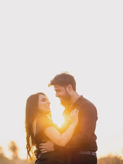 A joyful, sun-drenched portrait of a couple. The backlighting from the sun creates a beautiful flare, highlighting their happiness and love.