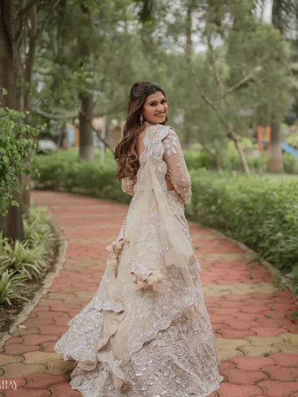 A lovely "look back" portrait of the bride as she walks through a green park. Her smile is infectious, and the shot beautifully captures the flow and detail of her white embroidered gown.