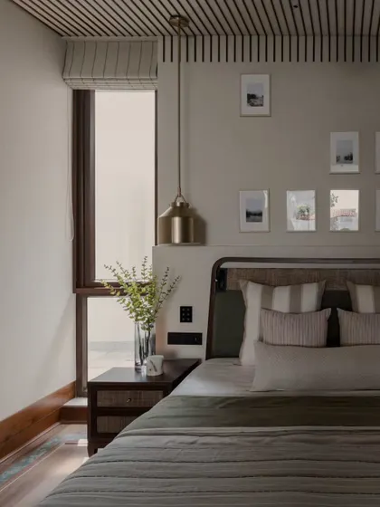 A close-up of the bedside in the Pràna project. The combination of the woven headboard, simple brass pendant, and fresh greenery creates a feeling of natural, effortless style.
