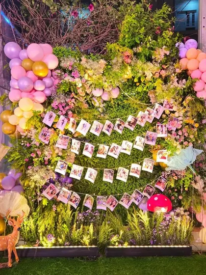 A creative photo wall I designed using a lush backdrop of greenery, flowers, and balloons. I hung strings of the couple's polaroid photos for guests to see.