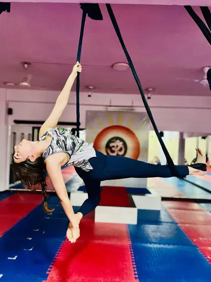 This graceful aerial pose, a variation of a side plank, builds incredible core and upper body strength. The student demonstrates focus and control while suspended.
