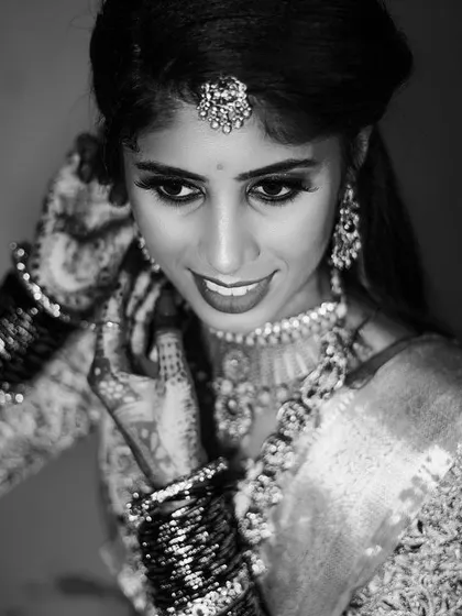 A beautiful black and white portrait of the bride adjusting her earring, a candid moment of preparation filled with grace.