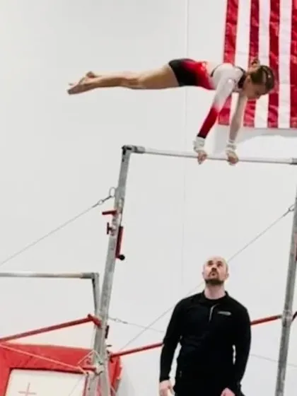 The uneven bars are a classic gymnastics event that builds incredible upper body strength and coordination. Here, one of our gymnasts demonstrates a perfect handstand hold, a key skill she mastered with the help of her coach.