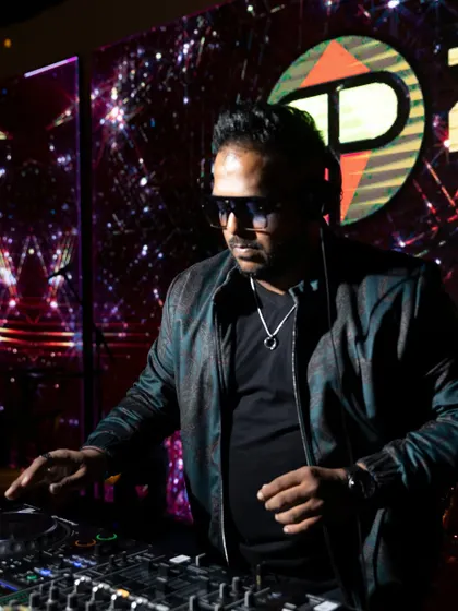 This is me in my element, focused on the mix at a corporate gala. I use professional Pioneer DJ gear to ensure the sound is perfect, while the custom LED visuals in the background create an immersive, high-energy atmosphere for your event.
