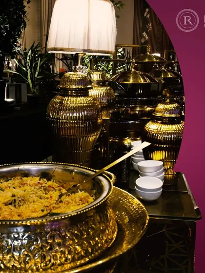 A close-up of a fragrant biryani served in an ornate, gold-finished vessel. We use exquisite serveware to elevate the presentation of traditional dishes, making them a feast for the eyes.