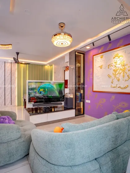 This living room design uses a bold purple accent wall and unique artwork to express personality. The rotatable TV unit is a smart, functional feature for an open-plan space.