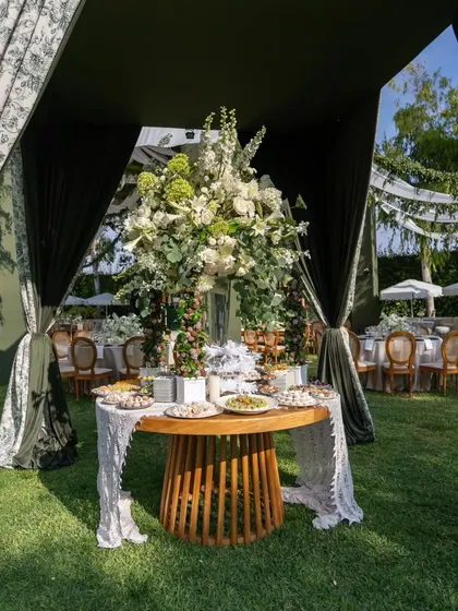 A central dessert station featuring a magnificent white floral arrangement. The table is framed by elegant drapes, making it a show-stopping focal point.