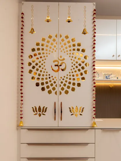 The closed view of the pooja unit, which is seamlessly merged with a crockery cabinet. The white doors with golden jaali work are both sacred and stylish.